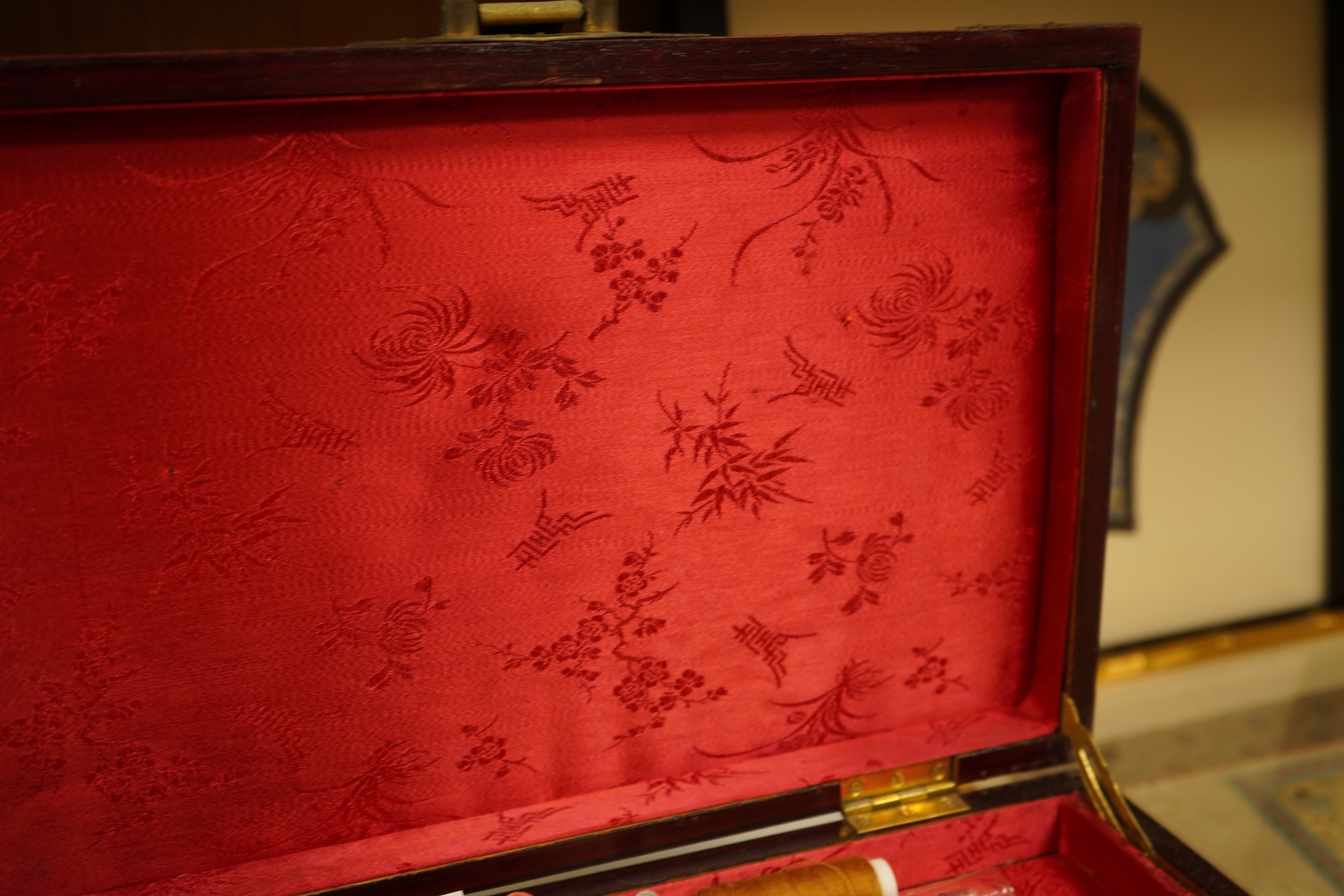A Chinese brass bound rosewood jewellery box with twin handles, the interior with sewing accessories and threads, 35cm wide